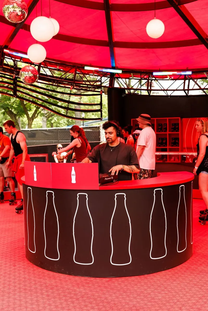 A DJ spinning behind the Coca-Cola bottle bar